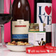 A close-up image featuring a bottle of Prosecco, a bottle labeled "LOVE," and a jar of salted nut mix. A glass is partially visible alongside a bowl filled with mixed nuts. The background is bright pink, creating a festive atmosphere. Red ribbon with the text “all my love” is also present in the composition. A close-up image featuring a bottle of Prosecco, a bottle labeled "LOVE," and a jar of salted nut mix. A glass is partially visible alongside a bowl filled with mixed nuts. The background is bright pink, creating a festive atmosphere. Red ribbon with the text “all my love” is also present in the composition.